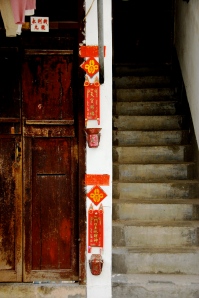 Beautiful textured wooden doorway, rich red adornments and rickety staircase